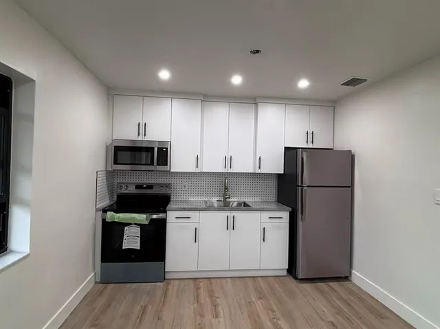 a kitchen with a sink a stove a refrigerator and cabinets