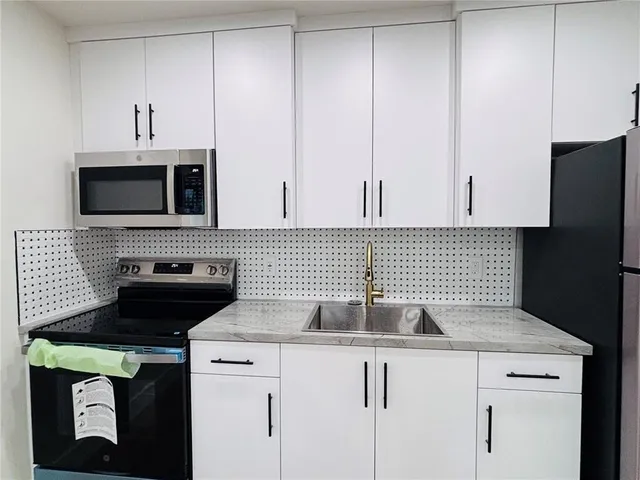 a kitchen with appliances a sink and cabinets