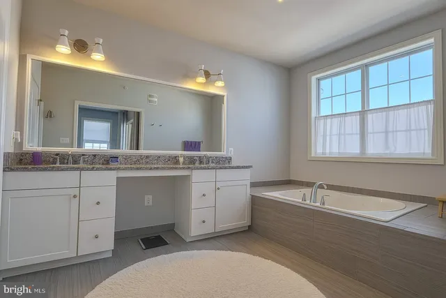 a spacious bathroom with a granite countertop sink mirror and bathtub