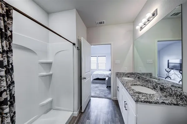 a bathroom with a granite countertop sink a mirror and shower