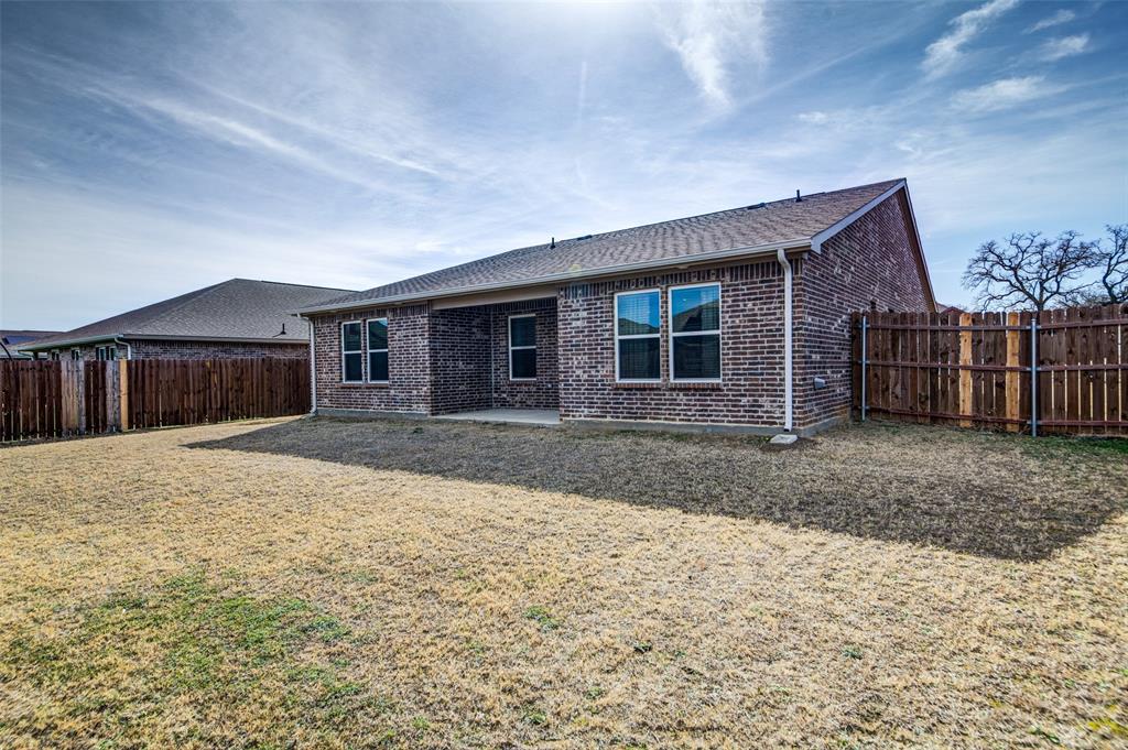 905 Avagail Avenue Springtown, TX 76082 - Photo 25 of 26 Back of property with a patio area, brick siding, a shingled roof, and a fenced backyard