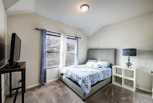 a bedroom with a bed tv and a window