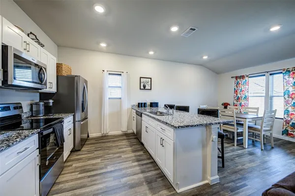 a kitchen with granite countertop a sink appliances and cabinets