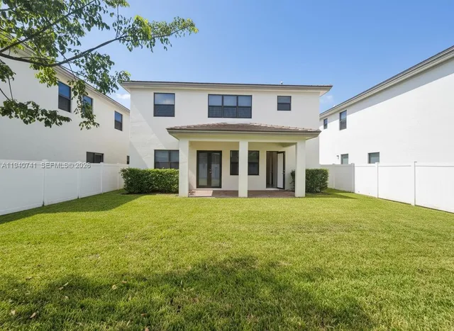 a view of an house with backyard and a tree