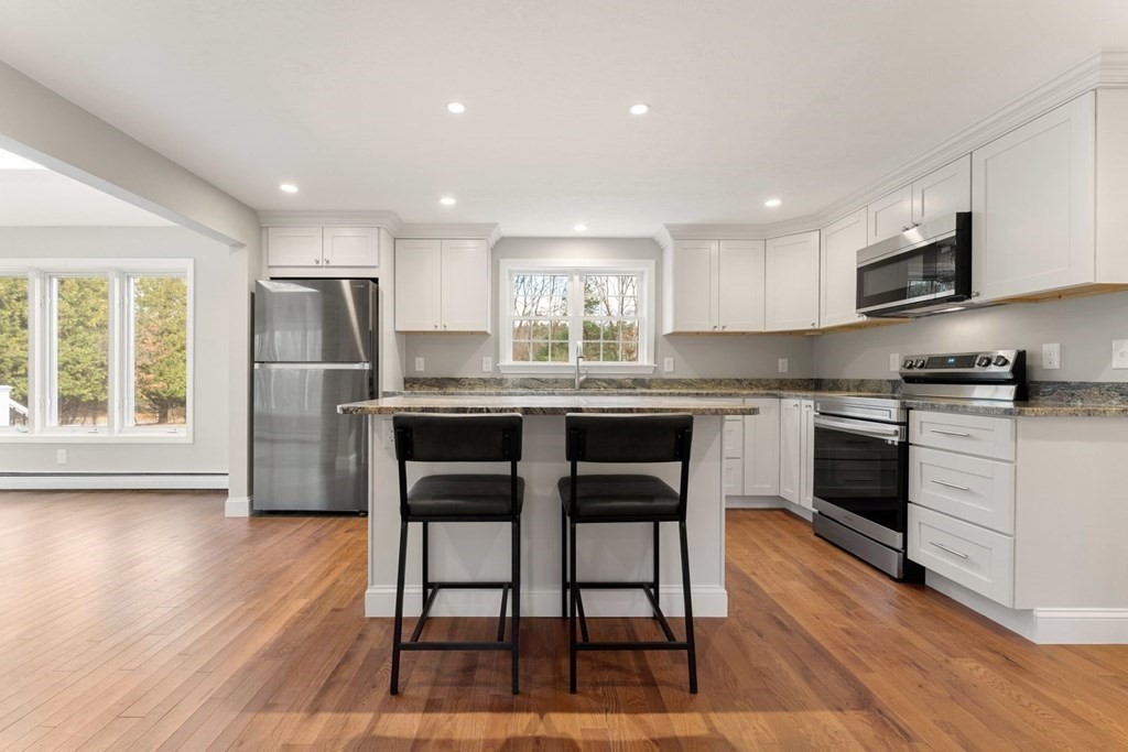 1069 Main Street Dunstable, MA 01827 - Photo 13 of 41 a kitchen with stainless steel appliances granite countertop a stove a sink a microwave a refrigerator and white cabinets with wooden floor