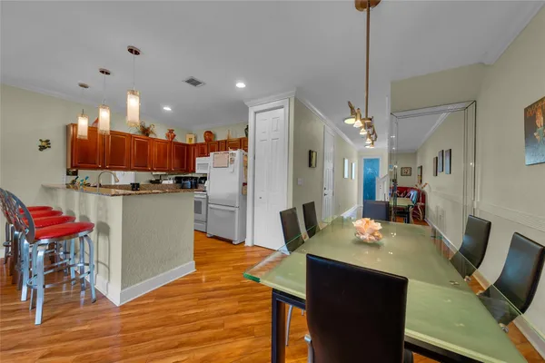 a kitchen with stainless steel appliances kitchen island granite countertop a table chairs and a refrigerator