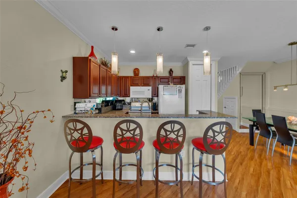 a group of chairs sitting in a kitchen with kitchen island stainless steel appliances refrigerator sink and wooden floor