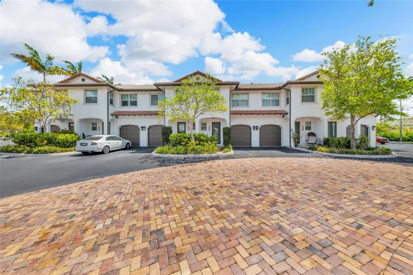 a front view of a building with garden and trees