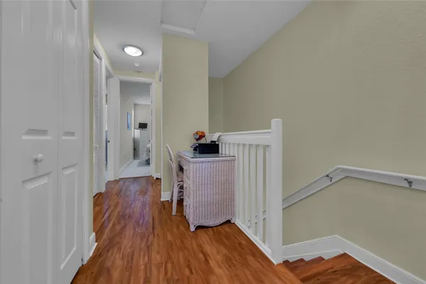 a view of a hallway to a livingroom with wooden floor and staircase