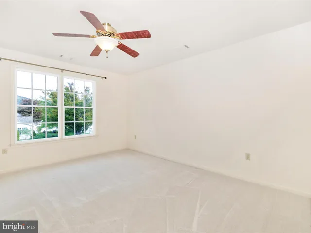 an empty room with ceiling fan and window