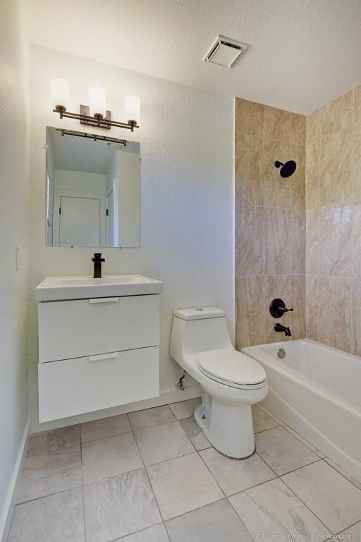 1601 East 10th Street Austin, TX 78702 - Photo 8 of 9 Bathroom featuring vanity, bathing tub / shower combination, a textured ceiling, a textured wall, and light tile patterned floors