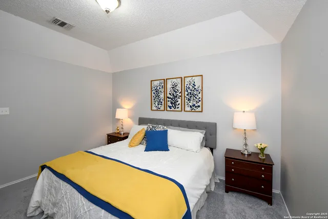 a bedroom with a bed and a lamp on dresser