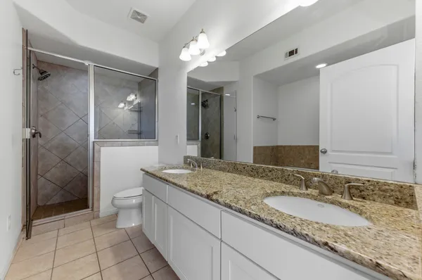 a bathroom with a granite countertop sink a toilet a mirror and shower
