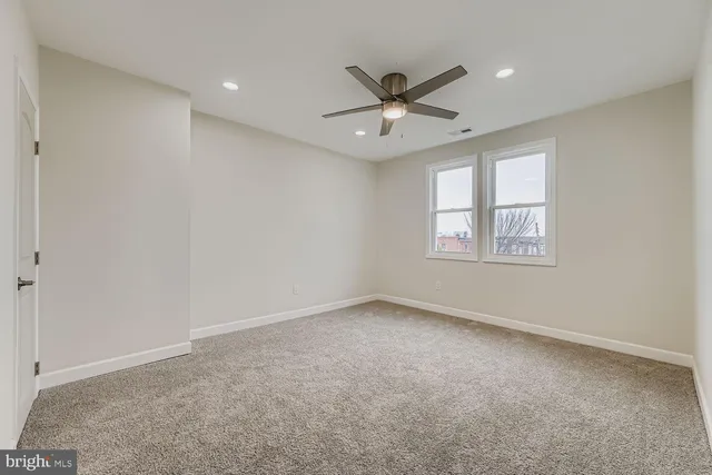 an empty room with windows and fan