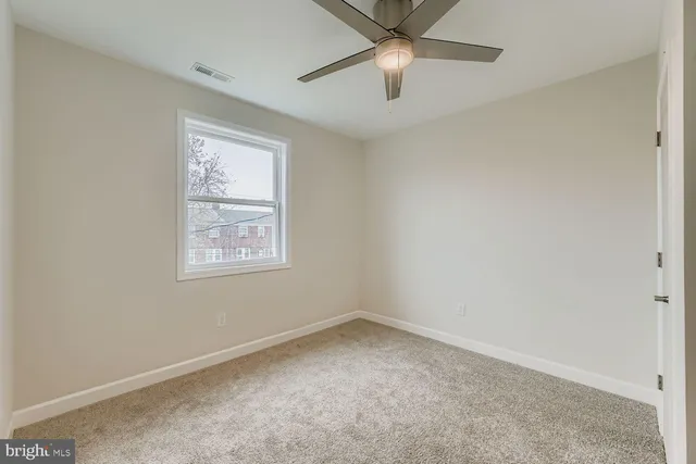 an empty room with a window and a fan