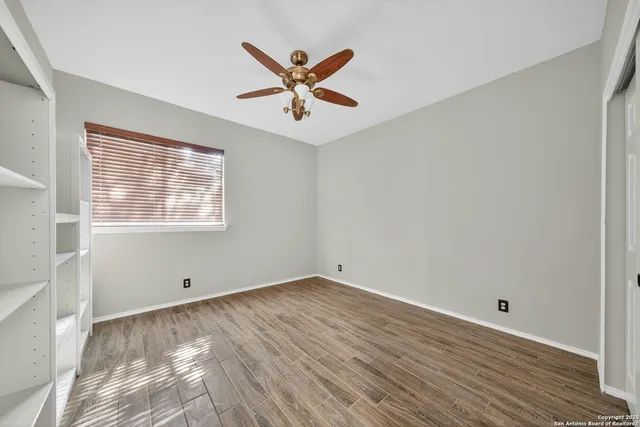 an empty room with windows and fan