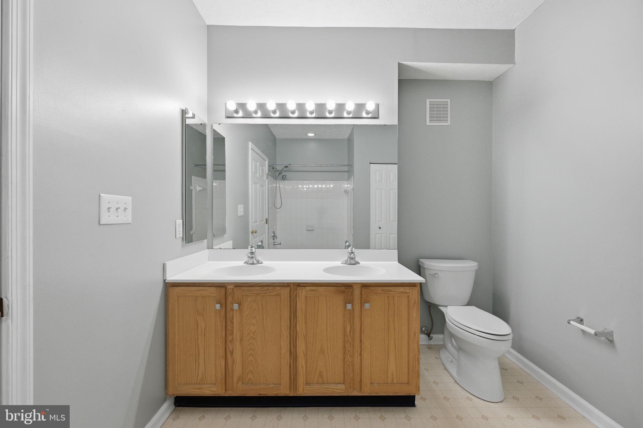2402 Chestnut Terrace Court, Unit 202 Odenton, MD 21113 - Photo 16 of 24 a bathroom with a granite countertop sink a toilet and a mirror