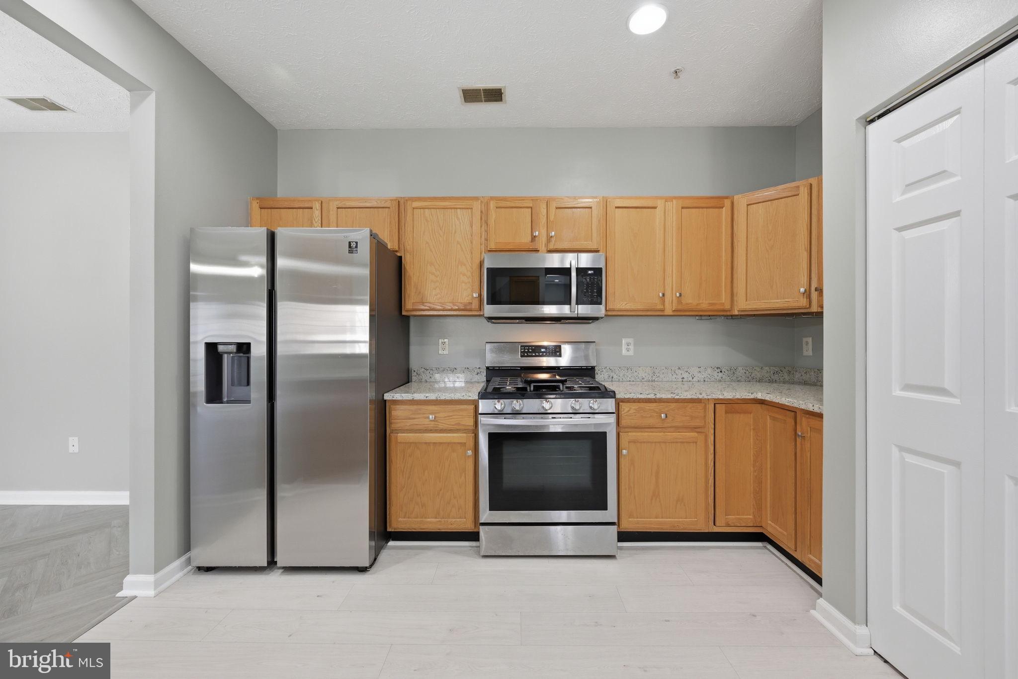 2402 Chestnut Terrace Court, Unit 202 Odenton, MD 21113 - Photo 4 of 24 a kitchen with stainless steel appliances granite countertop a refrigerator stove and microwave