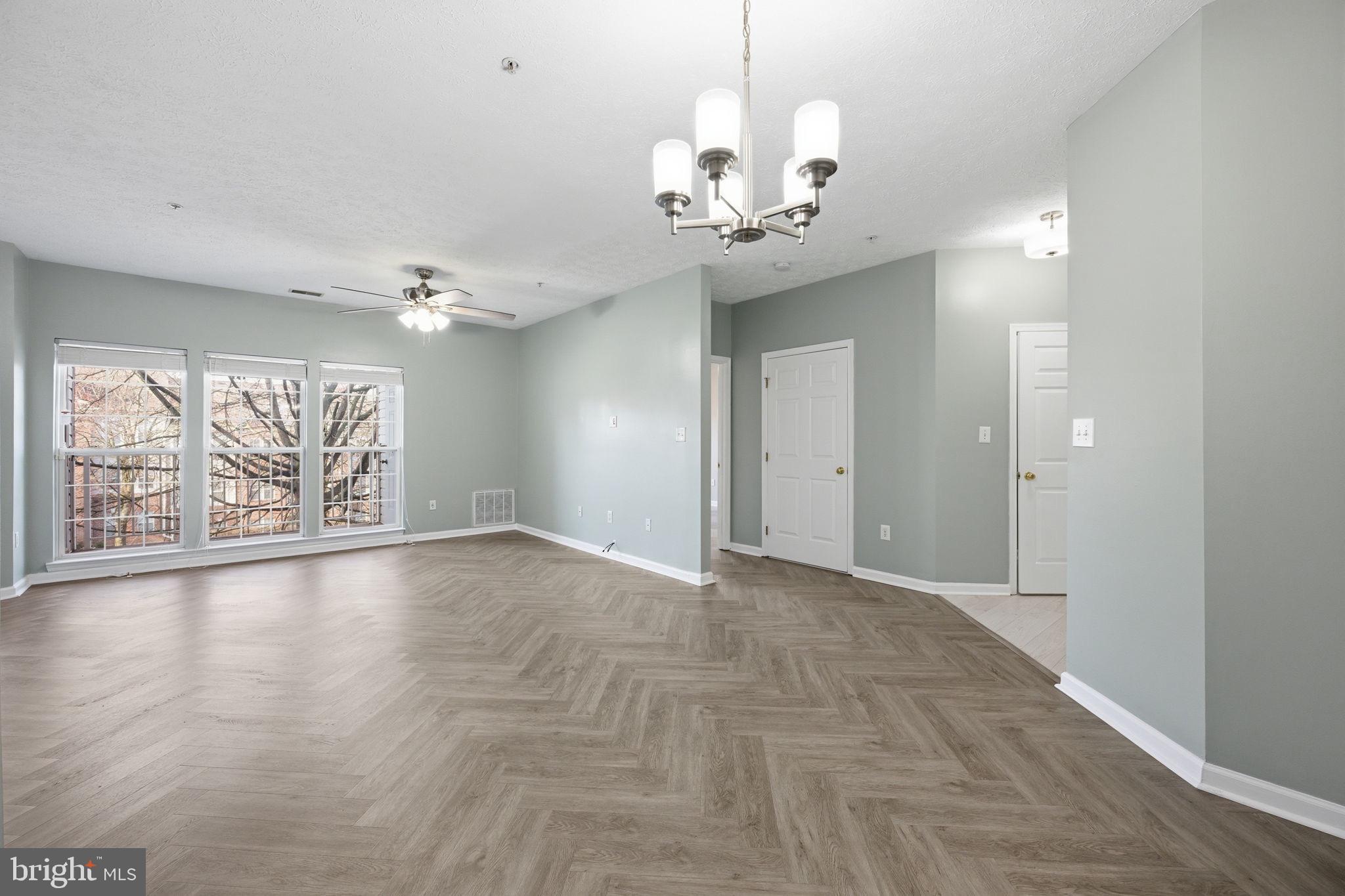 2402 Chestnut Terrace Court, Unit 202 Odenton, MD 21113 - Photo 6 of 24 a view of an empty room with a chandelier fan and kitchen view