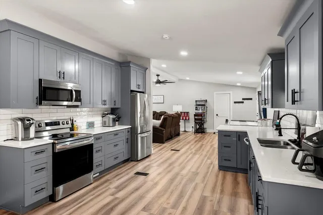 a kitchen with kitchen island granite countertop a sink appliances cabinets and a counter top space