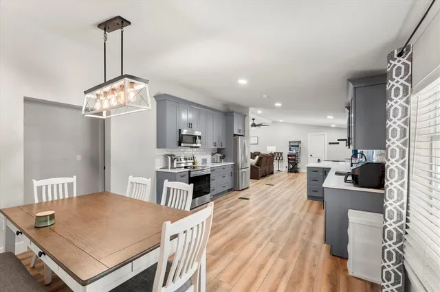 a open kitchen with stainless steel appliances granite countertop a stove a refrigerator a kitchen island a sink dishwasher a dining table and chairs with wooden floor