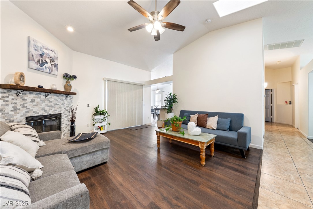 3481 Winery Road Pahrump, NV 89048 - Photo 20 of 34 Living room with ceiling fan, a stone fireplace, high vaulted ceiling, wood finished floors, and a skylight