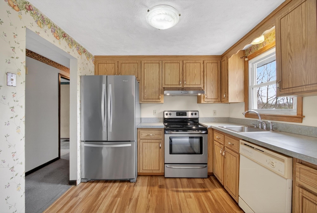 73 Nashua Road Pepperell, MA 01463 - Photo 11 of 33 a kitchen with a refrigerator wooden floor a stove and a window
