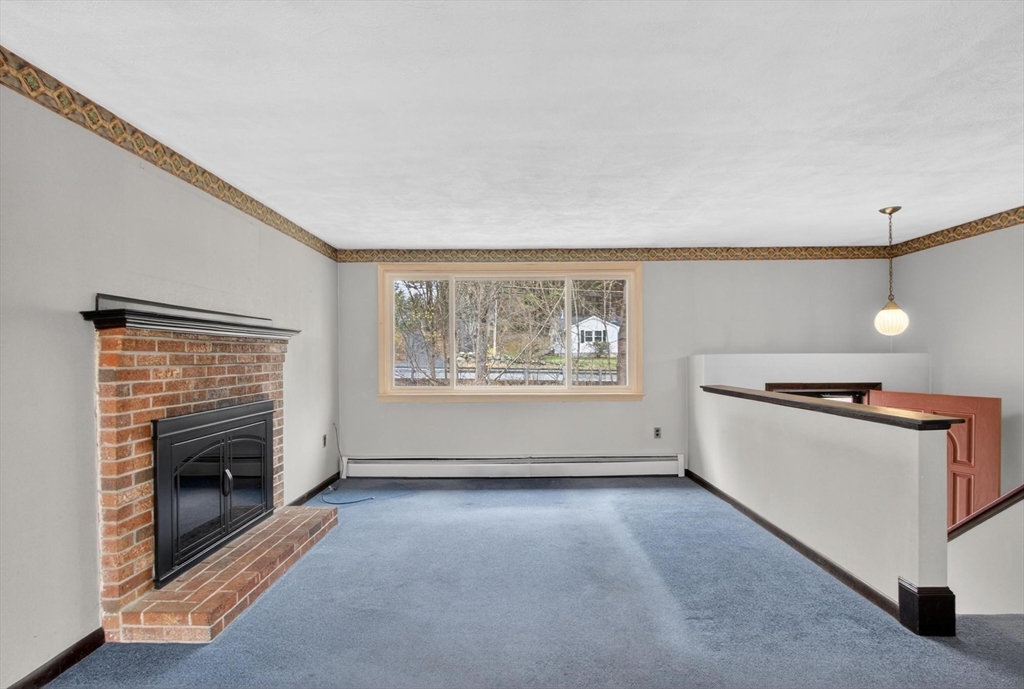 73 Nashua Road Pepperell, MA 01463 - Photo 5 of 33 a view of a livingroom with furniture a fireplace and wooden floor