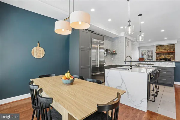 a kitchen with stainless steel appliances granite countertop a dining table chairs and a refrigerator