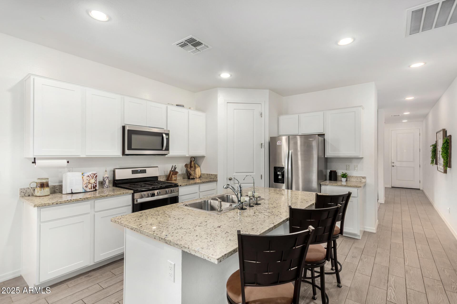 11517 East Unity Avenue Mesa, AZ 85212 - Photo 9 of 48 a kitchen with stainless steel appliances kitchen island granite countertop a sink dishwasher a stove a refrigerator with a dining table and chairs