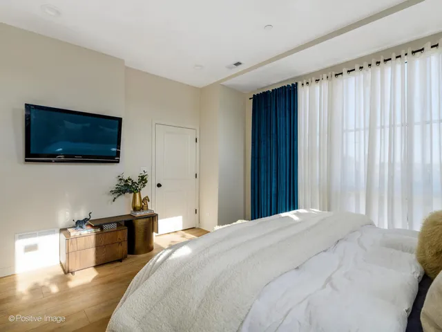a spacious bedroom with a bed and a flat screen tv