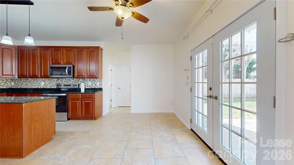 a kitchen with stainless steel appliances granite countertop a refrigerator a sink dishwasher a stove and a large window with wooden floor