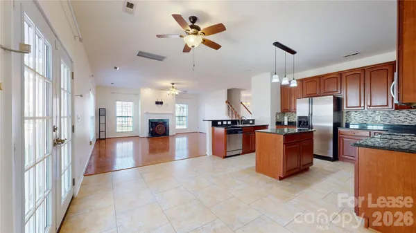a view of kitchen with stainless steel appliances granite countertop a refrigerator a stove top oven a sink dishwasher and white cabinets with wooden floor