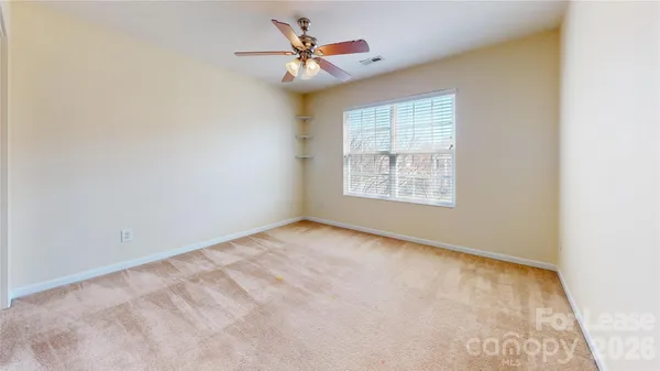 an empty room with windows and fan