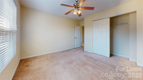 an empty room with windows and fan