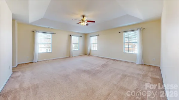 an empty room with windows and ceiling fan