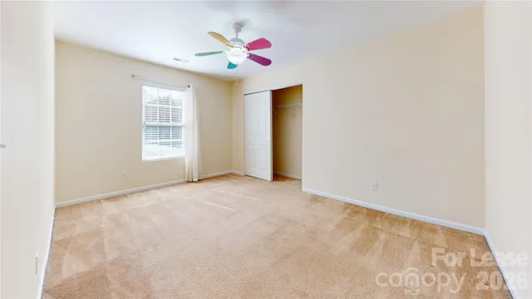 an empty room with windows and fan