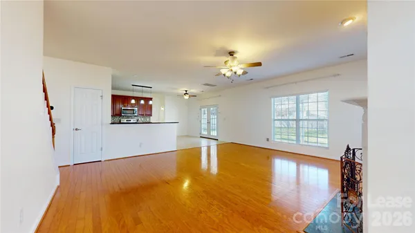a view of an empty room with a window and wooden floor