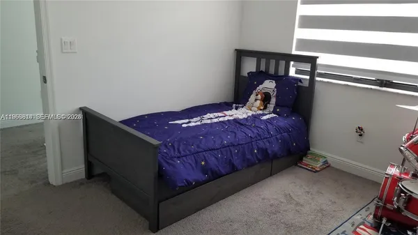 a bed sitting in a bedroom next to a window and a chandelier