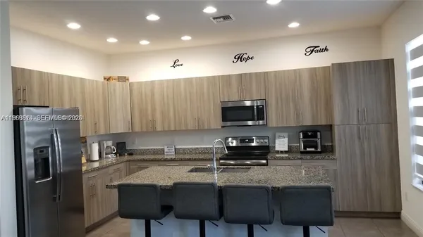 a kitchen with stainless steel appliances granite countertop a stove a sink a microwave a refrigerator and cabinets