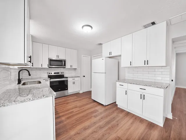 a large kitchen with kitchen island a large window a sink and stainless steel appliances