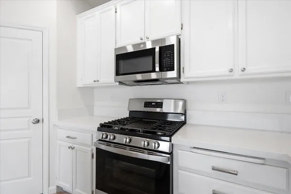 a kitchen with stainless steel appliances white cabinets and stove