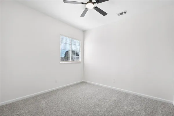 an empty room with a window and a fan