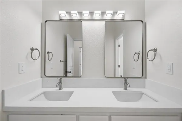a bathroom with double vanity sinks and a mirror