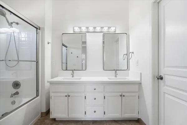 a bathroom with a double vanity sink mirror and shower