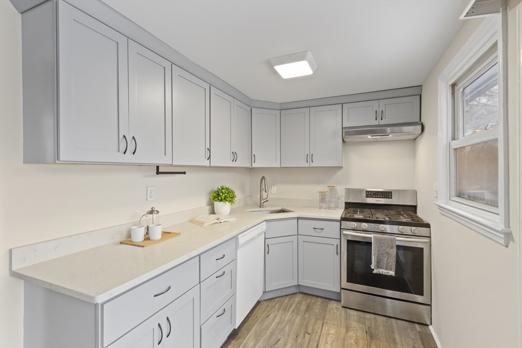 58 Neillian Way, Unit 58 Bedford, MA 01730 - Photo 3 of 23 a kitchen with cabinets stainless steel appliances a sink and wooden floor