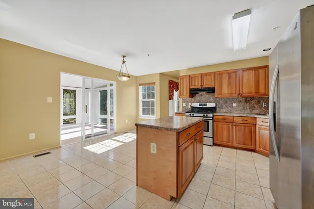 a kitchen with stainless steel appliances granite countertop a stove top oven a sink dishwasher a dining table and chairs with wooden floor