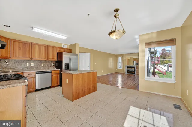 a kitchen with stainless steel appliances granite countertop a stove a sink dishwasher and a refrigerator with white cabinets