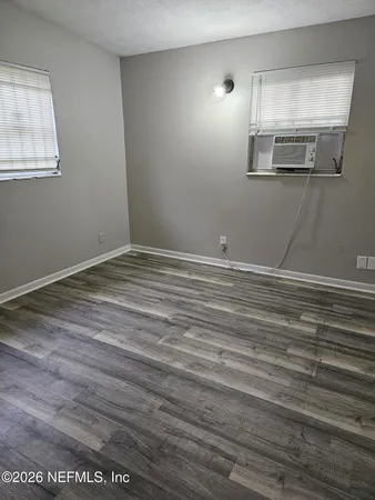 a view of an empty room with wooden floor and a window