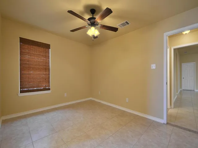 an empty room with a chandelier fan and windows